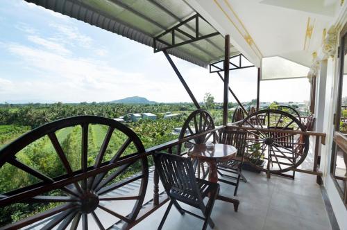 a porch with four chairs and a view of a vineyard at Little Saigon Hostel in Chau Doc