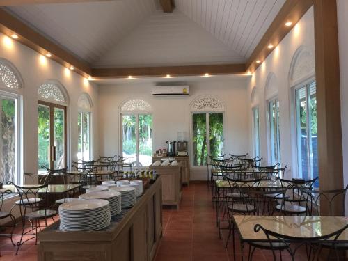 a dining room with tables and chairs and windows at Rommai Greenpark in Lampang