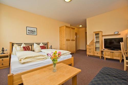 a bedroom with a bed with a vase of flowers on a table at Pension Lindenhof in Deutschfeistritz