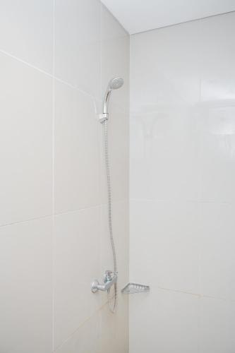 a shower with a shower head in a bathroom at Modern Studio Apartment at Tree Park Cikokol By Travelio in Kebun Nanas