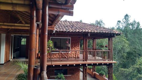 uma casa de madeira com um deque na floresta em La Casona Del Retiro em Medellín