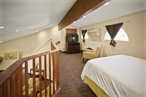 een slaapkamer met een bed en een trap met een televisie bij AmericInn by Wyndham Hill City Mt Rushmore in Hill City