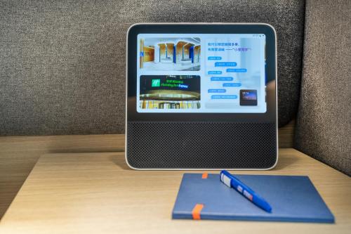 a tablet computer on a desk with a pen and a book at Holiday Inn Express Shanghai Pudong Zhangjiang by IHG - 20 minutes to New International Expo Center and Disneyland in Shanghai
