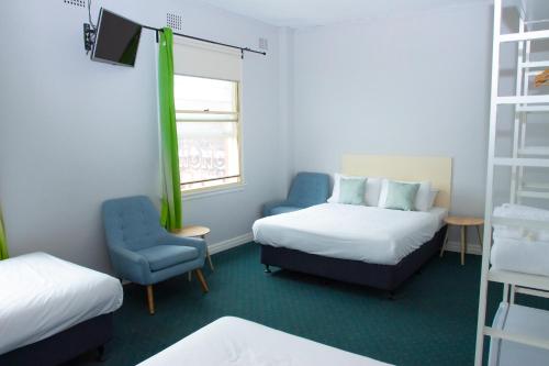 a small room with two beds and a chair at Grand Hotel Rockdale in Sydney