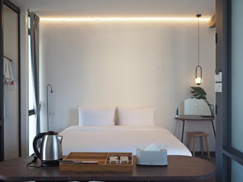 a bedroom with a white bed and a wooden table at Wonderwall Hotel in Chiang Mai