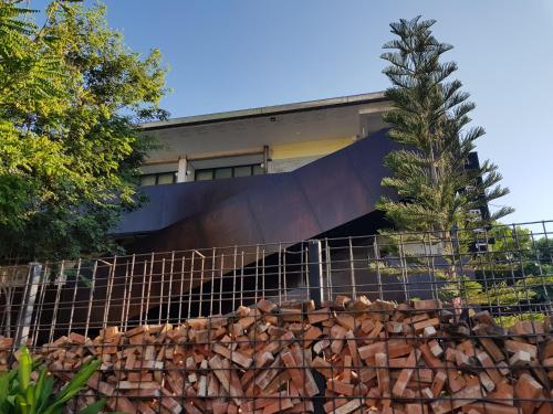 einen Zaun vor einem Gebäude mit einem Baum in der Unterkunft Wonderwall Hotel in Chiang Mai