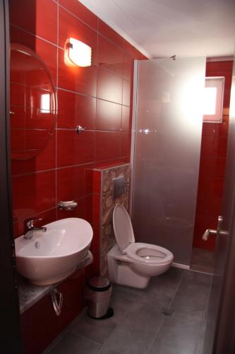 a red bathroom with a toilet and a sink at Aphrodite in Keramotí