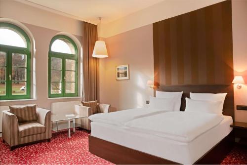 a bedroom with a large white bed and a chair at Schlosshotel Blankenburg in Blankenburg