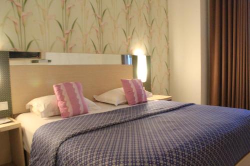 - une chambre avec un lit doté d'oreillers roses et blancs dans l'établissement Hotel Dewarna Sutoyo Malang, à Malang