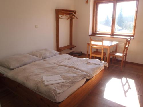 Cama en habitación con mesa y ventana en Švehlíkova Chata, en Nové Hutě