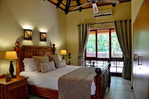 een slaapkamer met een bed en een groot raam bij Cambalala - Luxury Units - in Kruger Park Lodge - Serviced Daily, Free Wi-Fi in Hazyview