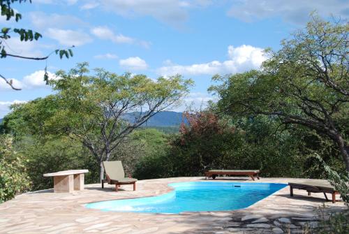 una piscina con 2 bancos y una mesa de picnic en Ohange Namibia Lodge, en Otavi