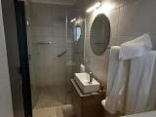 a bathroom with a shower and a sink and a mirror at Guesthouse Indongo Swakopmund in Swakopmund