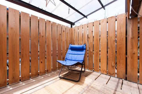 a blue chair sitting on a deck with a fence at Fushimi Inari House in Kyoto