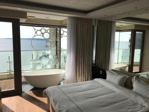 ein Schlafzimmer mit einer Badewanne und einem großen Fenster in der Unterkunft Ocean Star Condominium in Seogwipo