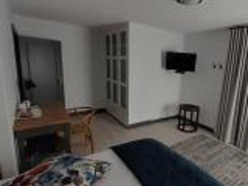 a bedroom with a bed and a desk and a television at Guesthouse Indongo Swakopmund in Swakopmund