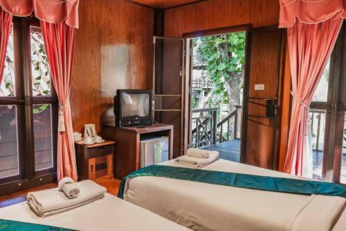 two beds in a room with a television and a balcony at Banviewnam Camping & Resort in Bān Tha Pu Deang