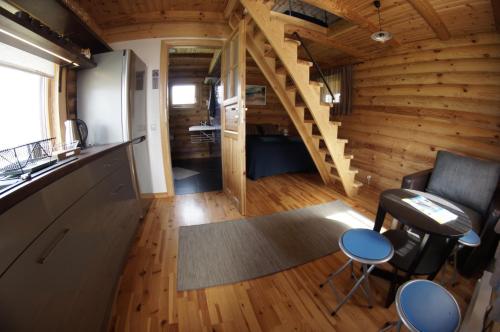 una cocina y una sala de estar con una escalera en una casa pequeña en Brīvdienu mājiņas Zemzari, en Jūrkalne