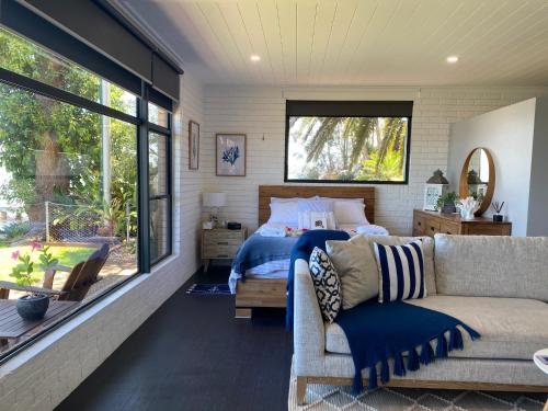 1 dormitorio con cama, sofá y ventana en Serenity by the Lake - Romantic Waterfront Couple's Getaway en Marks Point