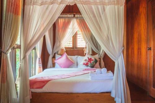 a bedroom with a bed with curtains and a window at Banviewnam Camping & Resort in Bān Tha Pu Deang