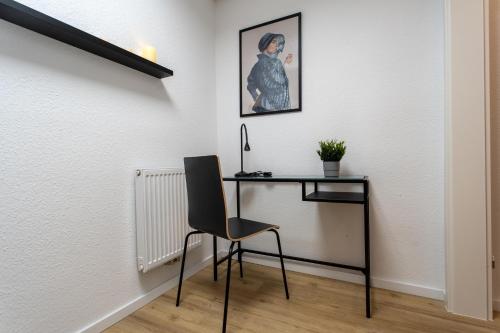 a desk with a chair next to a wall with a picture at Weberhof Ferienapartments in Rostrup am Westufer des Zwischenahner Meers in Bad Zwischenahn
