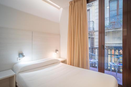 a bedroom with a bed and a large window at Hostal Fina in Barcelona