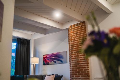 a living room with a couch and a brick wall at Weberhof Ferienapartments in Rostrup am Westufer des Zwischenahner Meers in Bad Zwischenahn