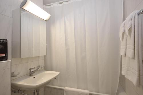 een witte badkamer met een wastafel en een douche bij PABS Résidences - Weinbergstrasse 68 (5MR) in Zürich