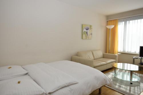 Habitación blanca con cama y sofá en PABS Résidences - Weinbergstrasse 68 (5MR), en Zúrich