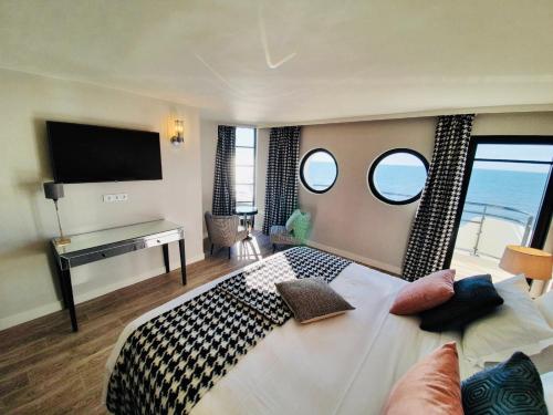 ein Schlafzimmer mit einem großen Bett und zwei Fenstern in der Unterkunft Le Paquebot in Villerville