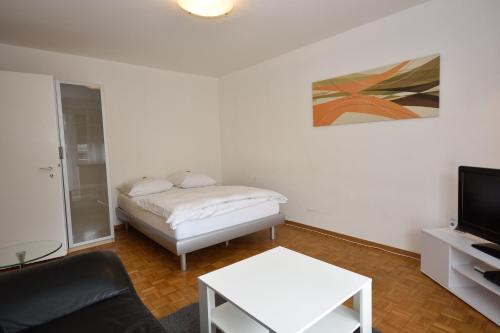 een woonkamer met een bed en een televisie bij PABS Résidences - Mühlebachstrasse 50 (1M) in Zürich