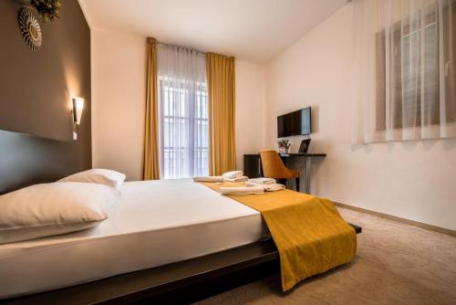 a bedroom with a bed with a yellow blanket on it at Hotel Nikola in Vodice