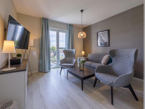 a living room with a couch and chairs and a tv at Zwei Wasser - Alte Seefahrtschule in Wustrow