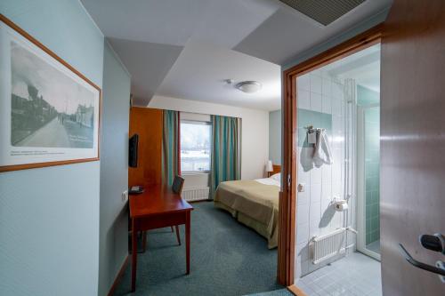 ハミナにあるSpaHotel Haminaのベッド、デスク、バスルームが備わるホテルルームです。