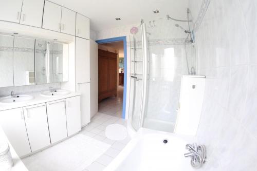 - une salle de bains blanche avec deux lavabos et une douche dans l'établissement Westhinder, à Wenduine