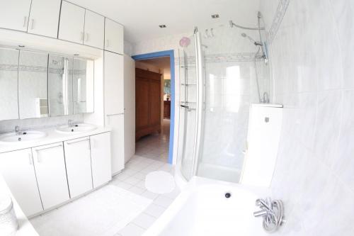 a white bathroom with two sinks and a shower at Westhinder in Wenduine