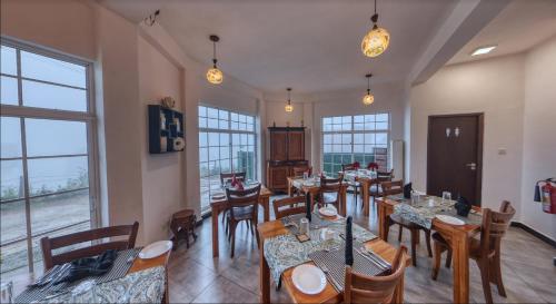 a dining room with tables and chairs and windows at Misthill Rest - Lavish Villa in Nuwara Eliya