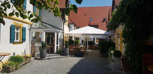a courtyard with a white umbrella and tables and chairs at Landgasthof Hotel Rittmayer in Hallerndorf