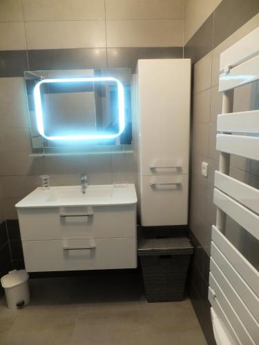 La salle de bains est pourvue d'un lavabo blanc et d'une lumière bleue. dans l'établissement Location saisonniere UZES 30700 6personnes, à Uzès