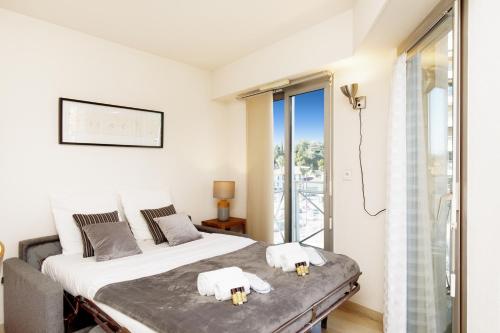 une chambre blanche avec un lit et un balcon dans l'établissement Colline Azur YourHostHelper, à Cannes