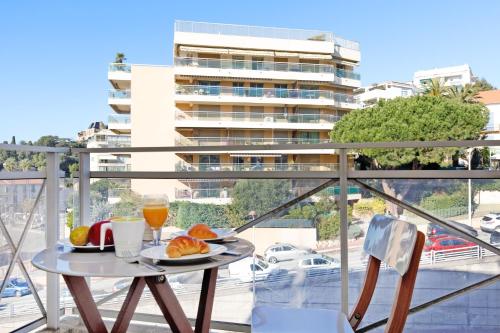 une table avec une assiette de nourriture sur un balcon dans l'établissement Colline Azur YourHostHelper, à Cannes