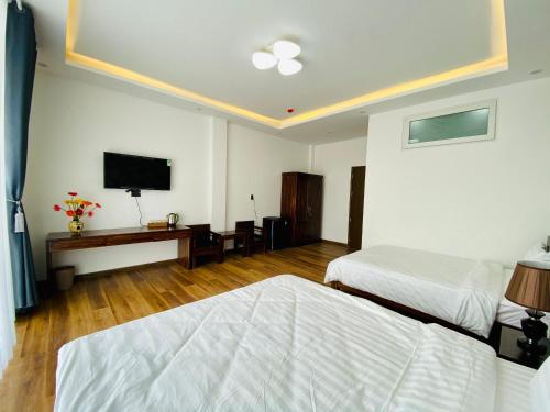 a bedroom with two beds and a flat screen tv at Mỹ Lan hotel in Da Lat