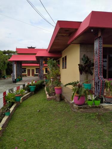 a house with potted plants in front of it at Hotel Olibert Parapat Ajibata Mitra RedDoorz in Parapat