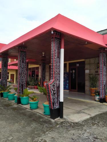 a building with a red roof and some plants at Hotel Olibert Parapat Ajibata Mitra RedDoorz in Parapat