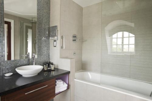 a white bath tub sitting under a window in a bathroom at Hotel du Vin Cannizaro House Wimbledon in London