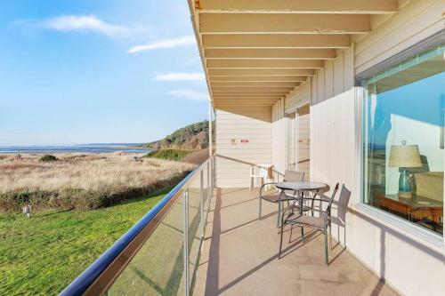 a balcony with a table and chairs and a view of the ocean at Heron Condo in Moclips