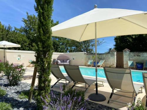 een patio met een zwembad en een parasol en stoelen bij Demeure de Beaulieu in Le Coudray-Macouard