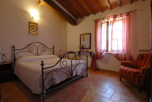 a bedroom with a bed and a chair and a window at La Piaggiola degli Olivi in Panicale