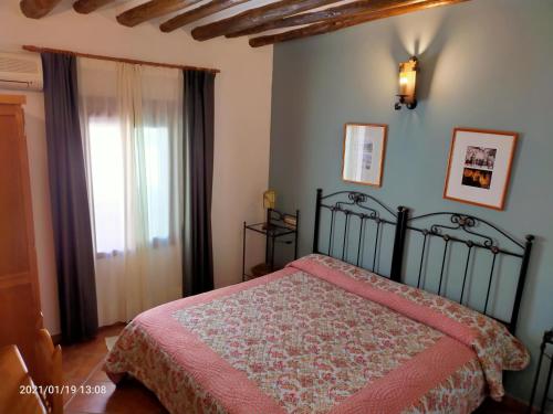 ein Schlafzimmer mit einem Bett mit einer rosa Tagesdecke und einem Fenster in der Unterkunft Hotel Rural Real de Laroles Nevada bike and treeking in Laroles