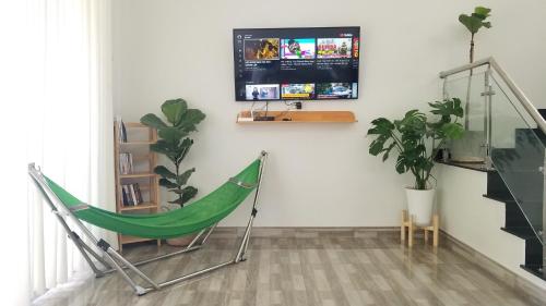 a green hammock in a living room with a tv at Nhiên Homestay - The Green House in Phú Quốc